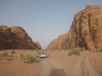 Cars on road by rock formations against sky