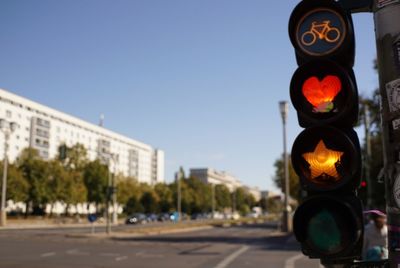 Road signal by street in city against clear sky