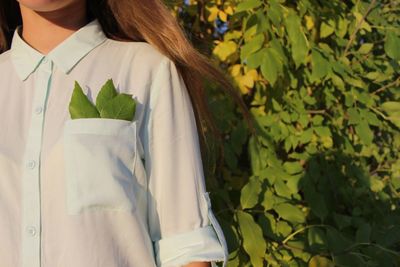 Midsection of woman standing with leaves in pocket