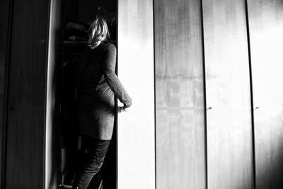 Rear view of woman standing against door