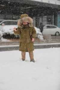 Happy boy enjoying snowfall in city