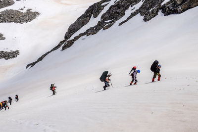 People walking on snowcapped mountain during winter