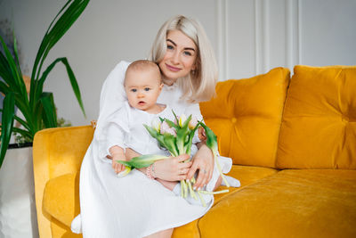 Portrait of young woman sitting on sofa at home