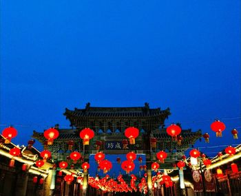 Low angle view of lanterns hanging against clear blue sky