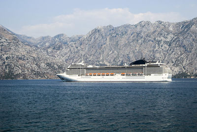 Ship sailing in sea against mountains