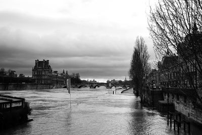 Bridge over river by buildings in city against sky