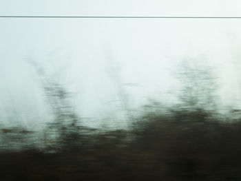 Blurred motion of trees against sky during winter
