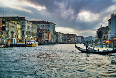 Boats in river against cloudy sky