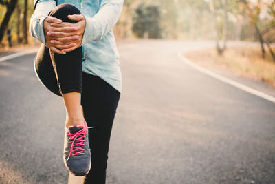 Low section of woman exercising on road