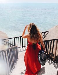 Woman standing on railing against sea