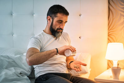 Portrait of senior man using mobile phone while sitting on bed at home