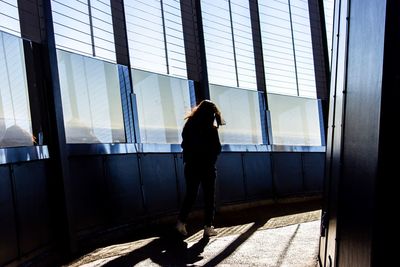 Rear view of silhouette man standing by window