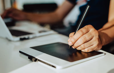 Midsection of businesswoman using graphics tablet