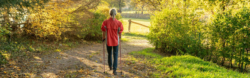 Rear view of woman walking on footpath during autumn