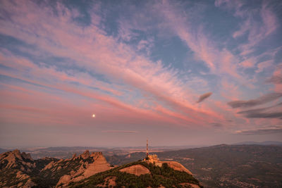 Scenic view of landscape against cloudy sky during sunset