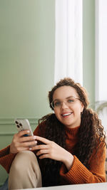 Portrait of smiling young woman using laptop at home