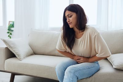 Young woman using laptop while sitting on sofa at home