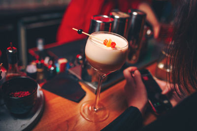 Midsection of woman sitting by drink at bar