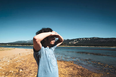 Man standing in water against clear blue sky