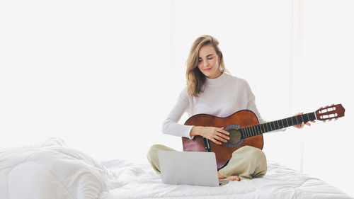 Young man playing guitar on bed