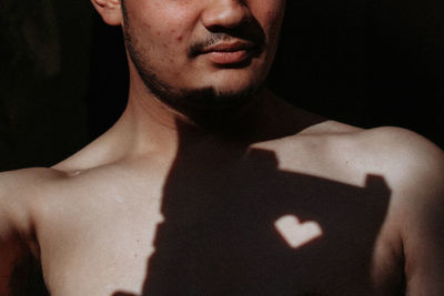 Close-up of shirtless man against black background