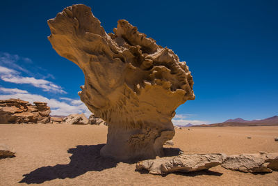 Sculpture on sand dune against blue sky