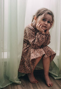 Portrait of young woman standing against curtain