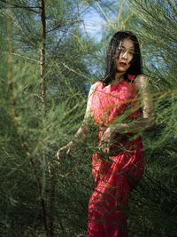 Young woman looking away while standing on tree in forest