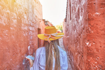 Rear view of woman standing against wall