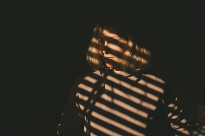 Portrait of woman standing against black background