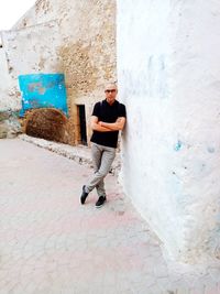 Portrait of young man standing against wall