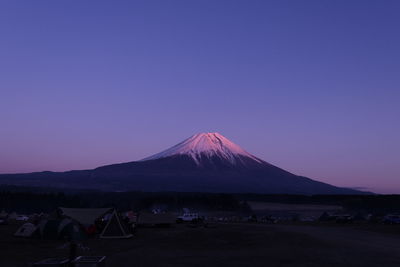 View of people on snowcapped mountain against blue sky
