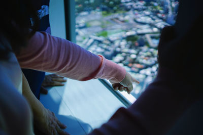 Cropped hand pointing outside while standing by window