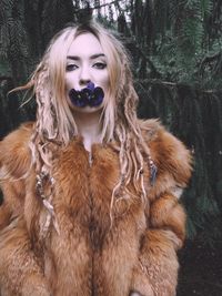 Portrait of young woman in fur coat carrying flowers in mouth