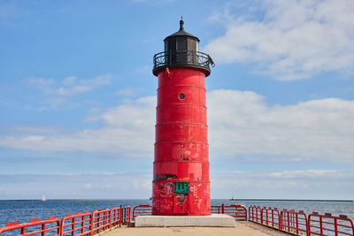 Lighthouse by sea against sky