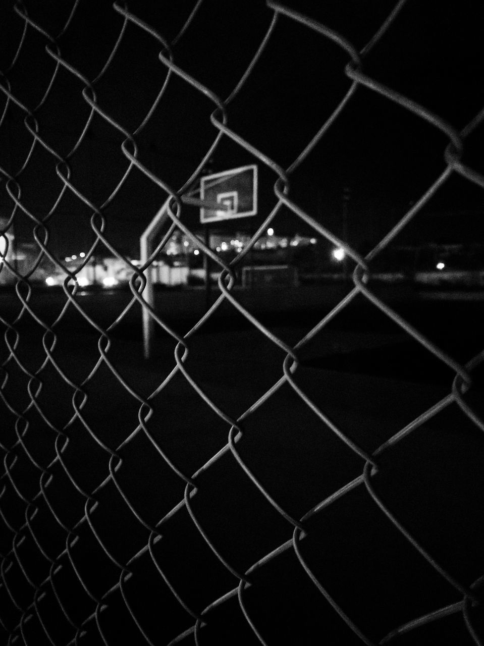 FULL FRAME SHOT OF CHAINLINK FENCE AT NIGHT SEEN THROUGH METAL GRATE