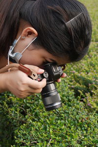 Portrait of woman holding camera on field