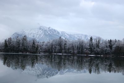 Scenic view of lake by snowcapped mountains against sky