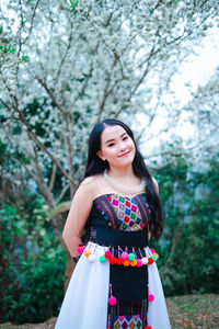 Portrait of a smiling young woman standing against trees