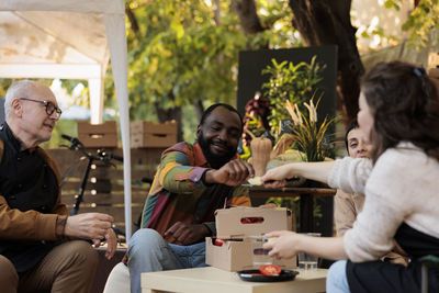 Portrait of smiling friends sitting on table