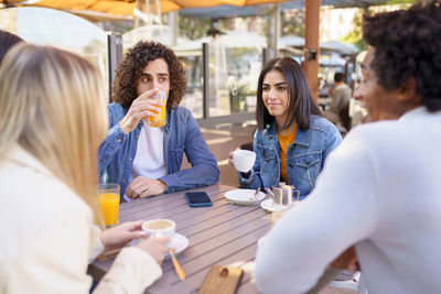 Side view of female friends using mobile phone while sitting at restaurant