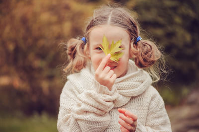 Portrait of happy girl holding leaf outdoors