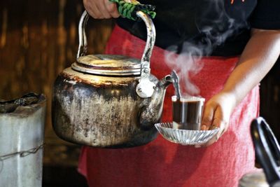 Midsection of woman pouring coffee in cup