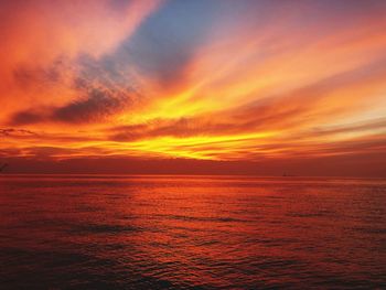 Scenic view of sea against dramatic sky during sunset