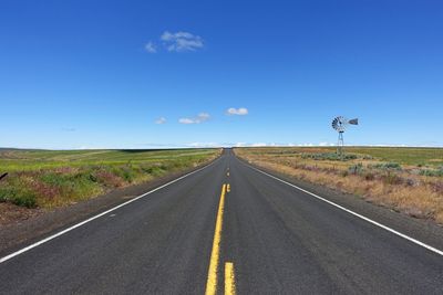 Road passing through landscape against blue sky