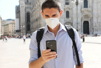 Man holding mobile phone in city