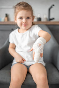 Portrait of cute baby boy sitting on sofa at home