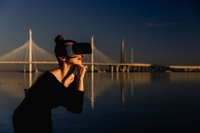 Rear view of woman standing against river at night