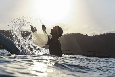 Female surfer in the ocean at sunset