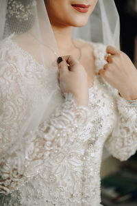 Midsection of bride in wedding dress